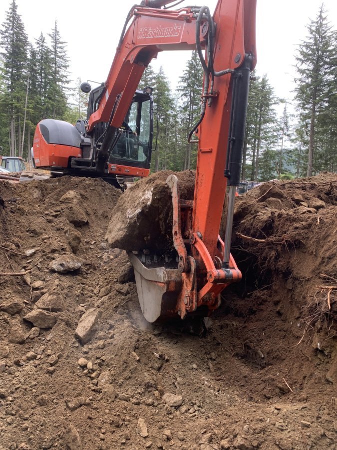 Excavator moving large rock